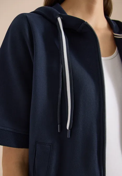 Kurzarm Sweatjacke mit Kapuze universal blue Nahaufnahme eines Oberkörpers mit dunkelblauer Kapuzenjacke (Kurzarm) über weißem Top.