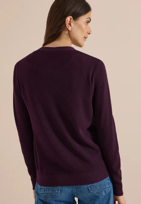 Frau von hinten in dunkelviolettem Pullover und blauer Jeans.