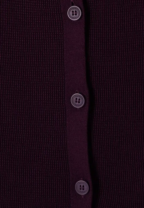 Nahaufnahme eines dunkelvioletten Strickcardigans mit vier vertikal angeordneten Knöpfen.