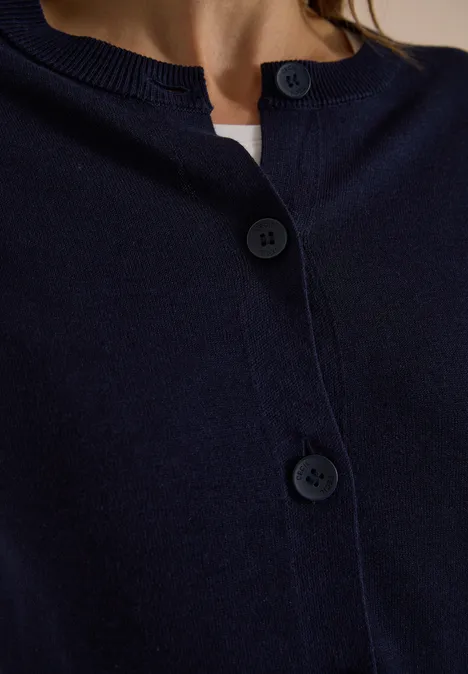 Diepblauwe cardigan met knopen en ronde hals in close-up.
