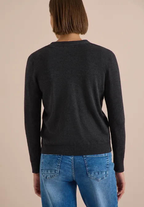 Rückenansicht einer Person mit kurzem Haar, die einen schwarzen Pullover und blaue Jeans trägt