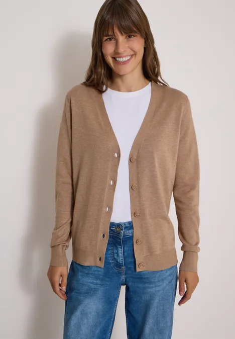Vest met V-hals en knoopsluiting creamy mocha melange Frau im hellbraunen Cardigan über weißem T-Shirt und blauen Jeans lächelt in die Kamera.