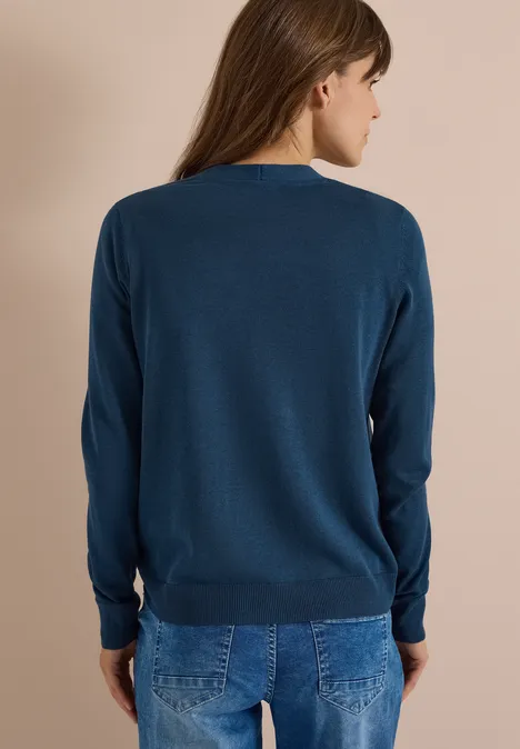 Cardigan mit V-Neck und Knopfleiste moonlight blue Frau von hinten in blauem Pullover und Jeans vor beigem Hintergrund