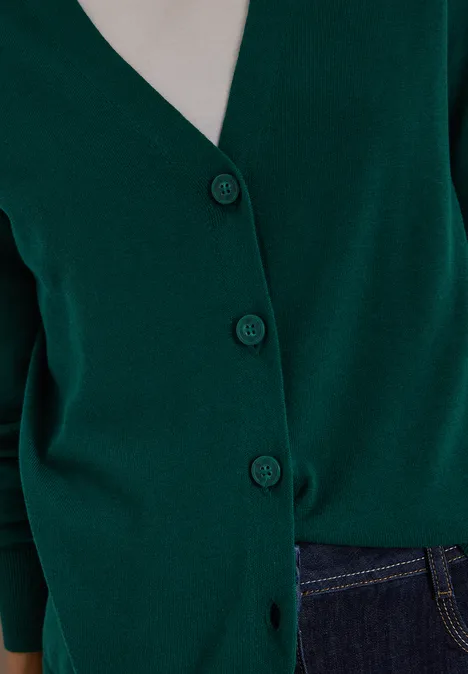 Dunkelgrüner Cardigan mit Knöpfen kombiniert mit dunkelblauer Jeans.
