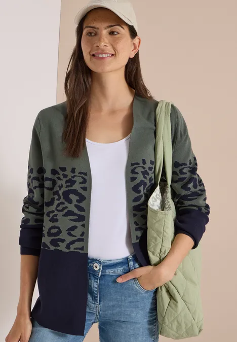 Offener Cardigan mit Jacquard-Muster dried olive green Frau in Cap, weißem Top, zweifarbigem Cardigan mit Leopardenprint, Jeans und gesteppte Tasche.