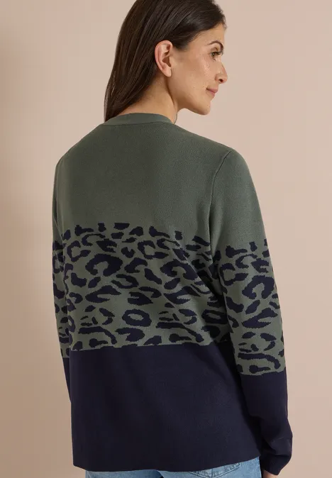 Offener Cardigan mit Jacquard-Muster dried olive green Frau mit dunklen Haaren von hinten, Pullover in Olivgrün mit Leopardenmuster und dunkelblauer unteren Partie.