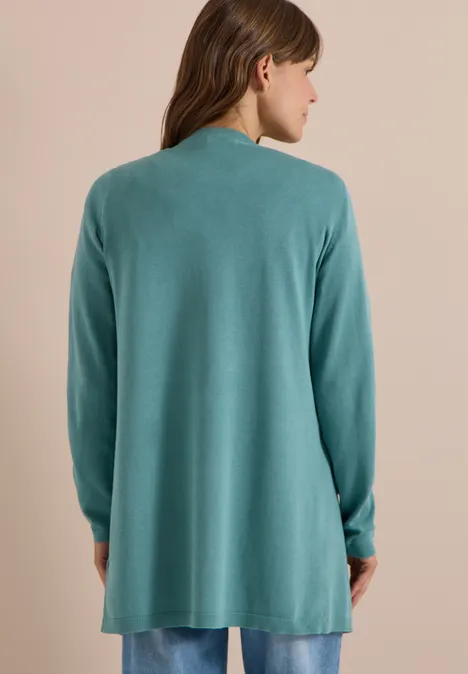 Vrouw van achteren draagt losvallende, lange mintgroene cardigan tegen neutrale achtergrond.