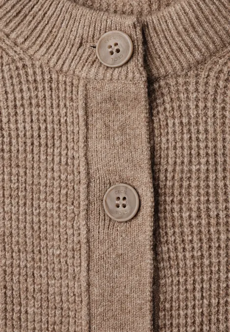 Nahaufnahme eines beigen/braunen Strickcardigans mit Knöpfen