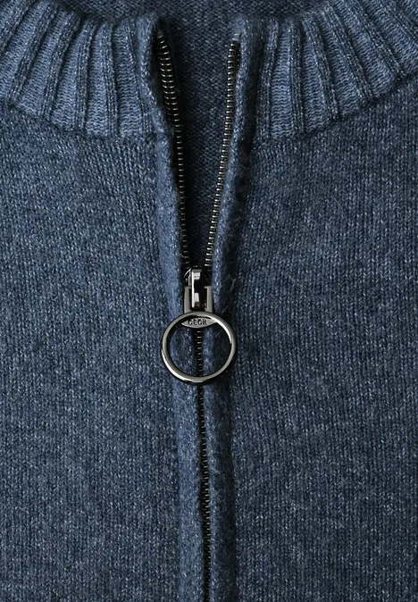 Close-up van een donkerblauwe gebreide trui met rits met ringtrekker en geribde kraag.