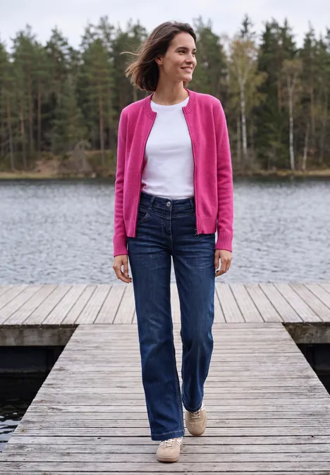 Langarm Cardigan mit Rundhals und Zipper pink flash Frau in Jeans, weißem Shirt und pinkem Cardigan steht auf einem Holzsteg am See, umgeben von Wald.