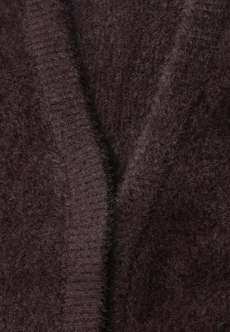 Nahaufnahme eines flauschigen, dunklen Strickstücks mit dezentem V-Ausschnitt