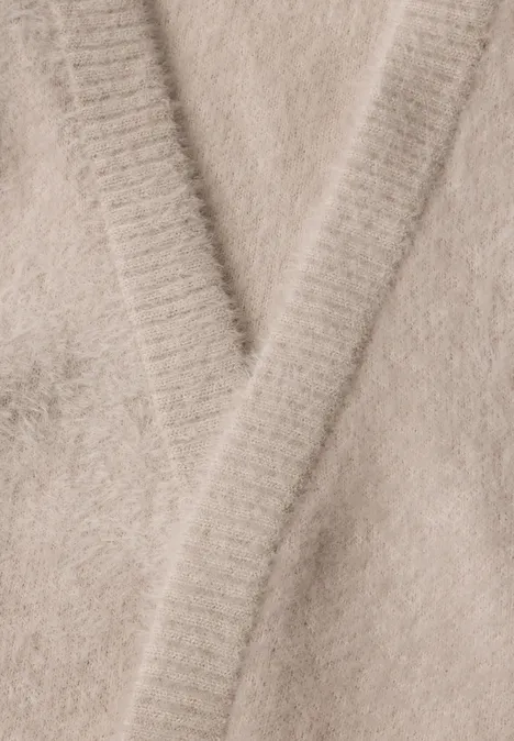 Nahaufnahme eines flauschigen, beigen Strickpullovers mit V-Ausschnitt.
