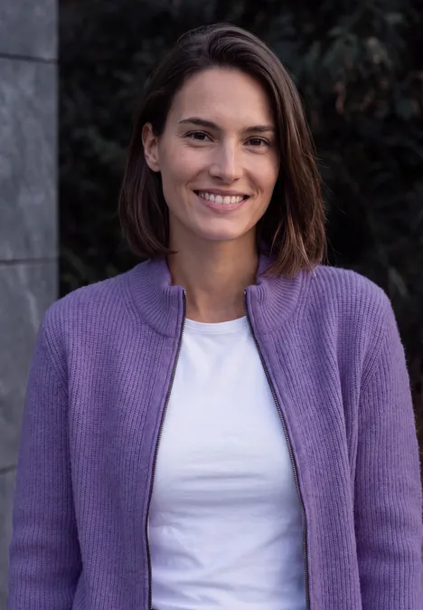 Cardigan mit Stehkragen und Zipper pastel lilac melange Eine Frau mit kurzem braunen Haar lächelt in einem lila Cardigan und weißem Shirt vor dunklem Hintergrund.