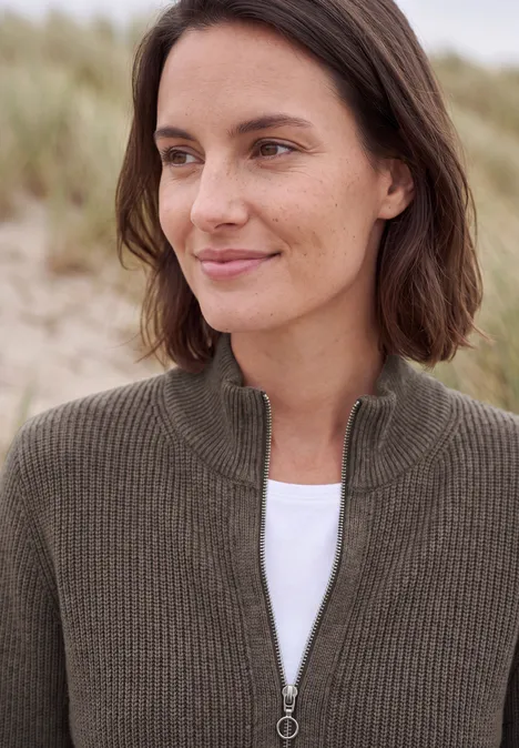 Cardigan mit Stehkragen und Zipper mushroom taupe melange Eine Frau mit braunem Strickpullover und weißem T-Shirt vor Sanddünen am Strand.