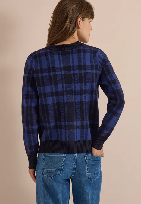 Person trägt blau-schwarz karierten Pullover und Jeans, von hinten zu sehen.