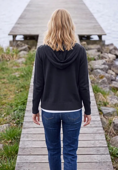 Langarm Cardigan mit Kapuze urban dark blue Junge Frau steht rücklings auf einem Holzsteg und blickt aufs Wasser.