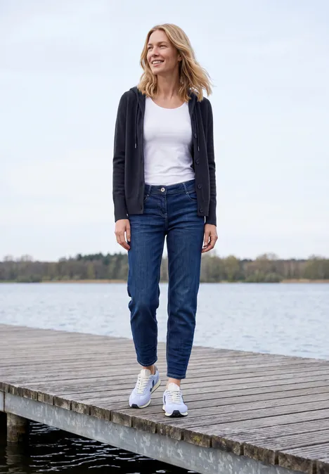 Langarm Cardigan mit Kapuze urban dark blue Frau läuft auf einem Steg am See, trägt Jeans, weißes Top und Cardigan
