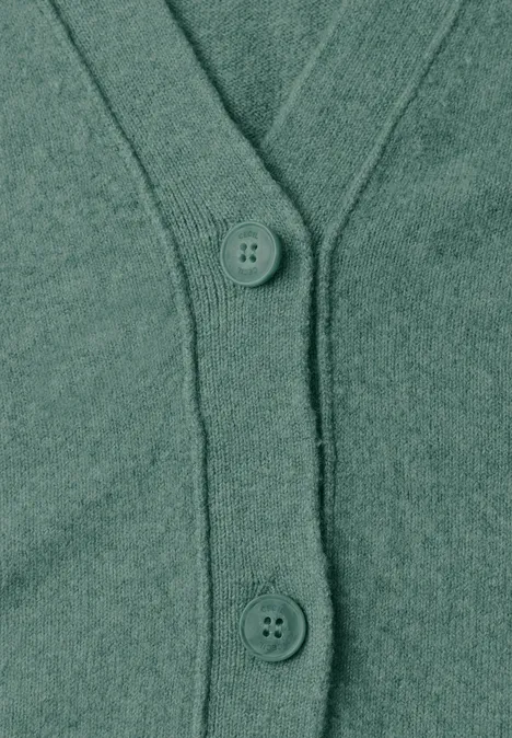 Grüne Strickjacke mit Knöpfen und V-Ausschnitt aus weichem Material.