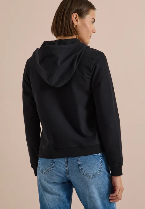 Frau von hinten in schwarzem Kapuzenpullover und blauen Jeans