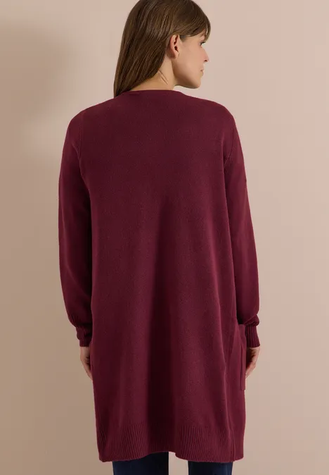 Cardigan long à la coupe ample red wine Femme de dos portant un cardigan ample bordeaux, manches longues, poches, longueur mi-cuisses.