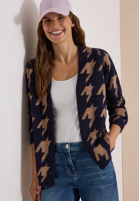 Femme souriante en gilet pied-de-poule, débardeur blanc, jean et casquette