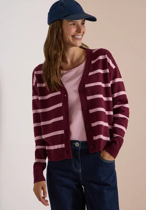 Vest met V-hals en strepen red wine melange Junge Frau in gestreiftem weinroten Cardigan, rosa Shirt, Jeans und Cap lächelnd.