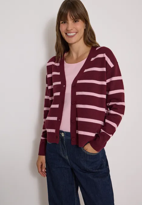 Vest met V-hals en strepen red wine melange Eine lächelnde Frau in bordeauxroter, gestreifter Strickjacke, rosa Top und jeansblauer Hose.