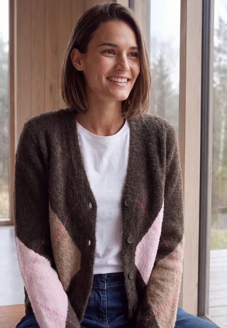 Cardigan mit V-Neck und Argyle-Muster truffle brown Lächelnde Frau im Strickcardigan, weißem Shirt und Jeans steht vor einem Fenster im hellen Raum.