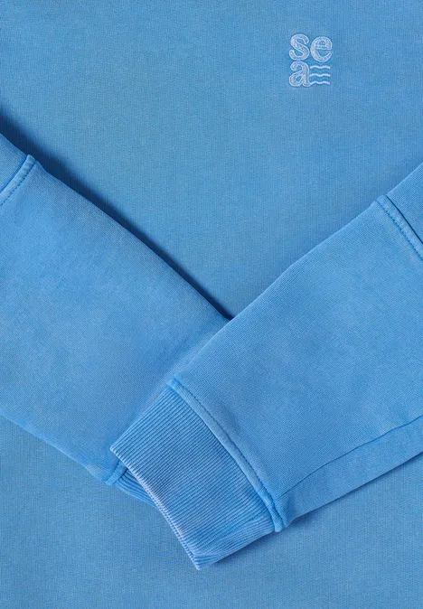 Pull bleu aux manches croisées, petit logo en haut à droite