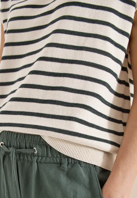 Nahaufnahme einer Person mit gestreiftem Oberteil und grüner Bundhose mit Kordelzug.