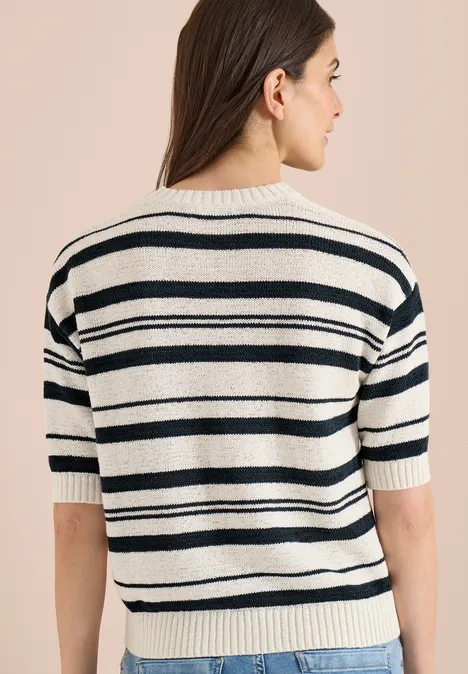 Rückenansicht einer Person mit kurzärmeligem, weiß-schwarz gestreiftem Strickshirt vor beigem Hintergrund.