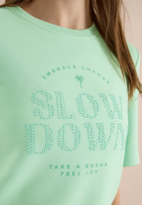 Hellgrünes T-Shirt mit gepunktetem Schriftzug "SLOW DOWN" und kleinem Motivationsspruch.