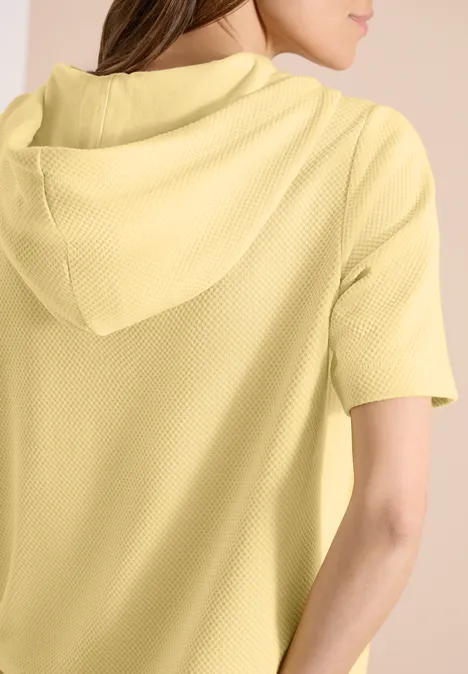 Frau in gelbem kurzärmligen Kapuzenpullover, von hinten