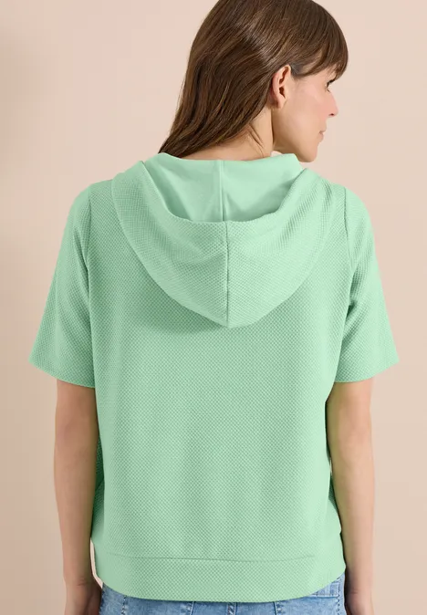 Frau von hinten in mintgrüner Kurzarm-Kapuzenjacke.