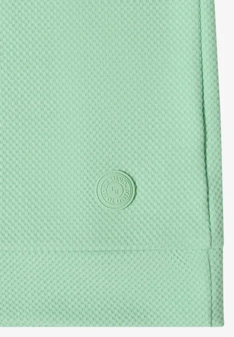 Nahaufnahme eines mintgrünen, strukturierten Stoffs mit eingearbeitetem kleinem Kreislogo.