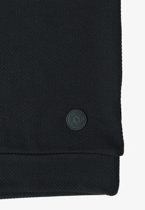 Schwarzes, strukturiertes Gewebe mit kleinem, rundem Logo am Saum