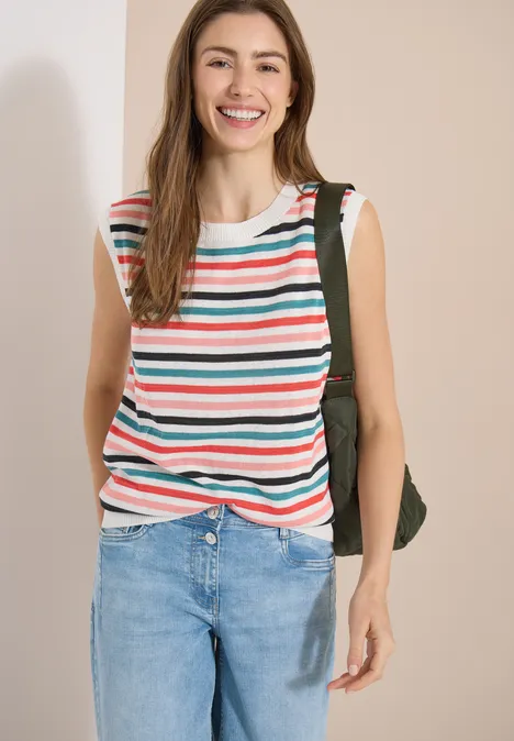 Pullunder mit Rundhals und Streifen raw sand beige Person trägt gestreiftes ärmelloses Top, blaue Jeans und Rucksack vor hellem Hintergrund.