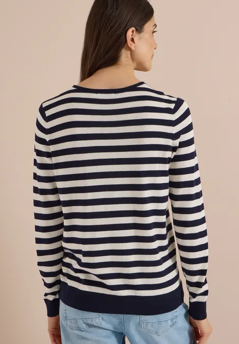 Pull à col rond et rayé urban dark blue Frau von hinten in maritim gestreiftem Langarmpullover (Marine/Weiß) und Jeans.