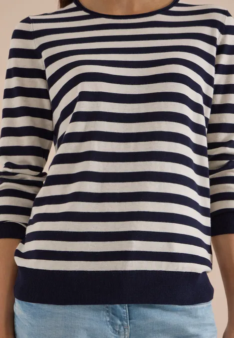 Pull à col rond et rayé urban dark blue Oberkörper einer Person in blau-weiß gestreiftem Dreiviertelarm-Pullover und Jeanshose