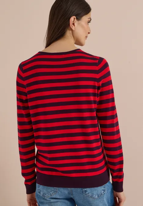 Pull à col rond et rayé eggplant red Frau von hinten in rot-dunkelblau gestreiftem Pullover mit langen Ärmeln und Jeans vor neutralem Hintergrund.