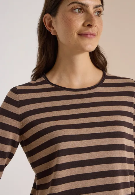 Pull à col rond et rayé truffle brown Frau in braun-schwarz gestreiftem Langarmshirt, die seitlich blickt.