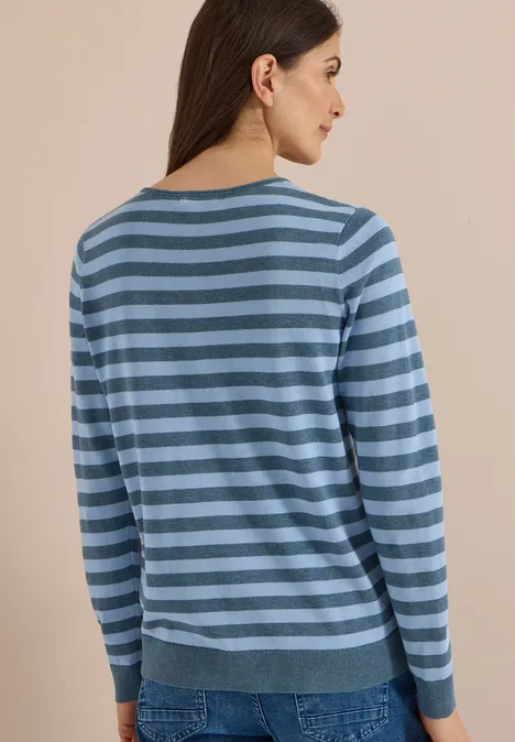 Femme de dos portant un pull rayé bleu et un jean.