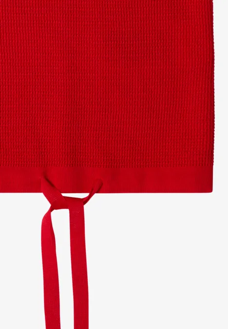 Rotes gestricktes Textil mit zwei Bändern, wirkt wie eine Schürze.