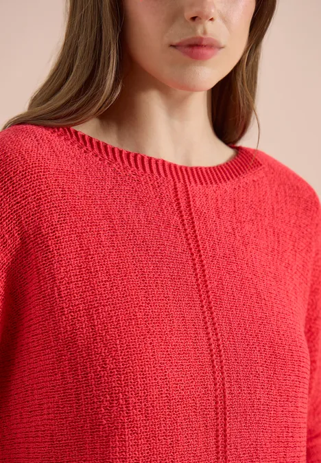 Gros plan d'une femme portant un pull rouge texturé.