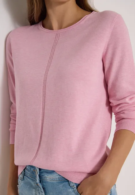 Pull femme rose à manches longues avec couture centrale discrète, porté avec un jean bleu