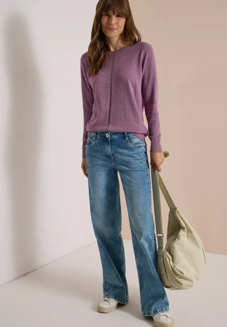 Basic Pullover mit Rundhals in Unifarbe lavender purple melange Frau in lila Pullover, blauen Jeans und weißen Sneakern trägt große beige Tasche vor hellem Hintergrund.