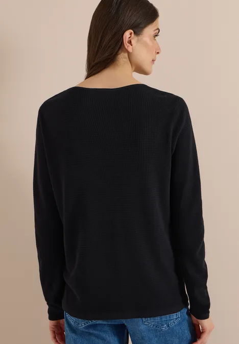 Frau von hinten in schwarzem Langarmshirt und blauen Jeans.