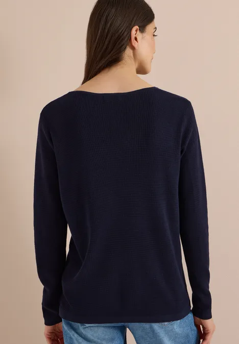 Rückenansicht einer Frau in marineblauem, langärmligem Pullover mit weiter, schlichter Form.