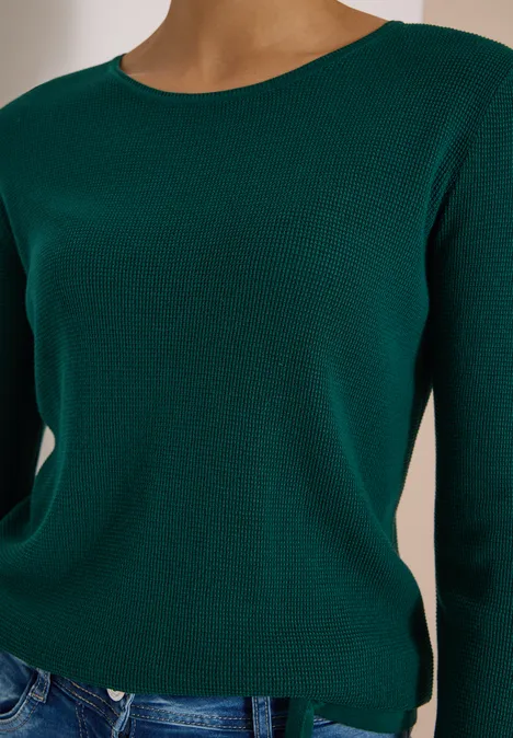 Dunkelgrüner Pullover mit Rundhalsausschnitt, kombiniert mit Jeans.