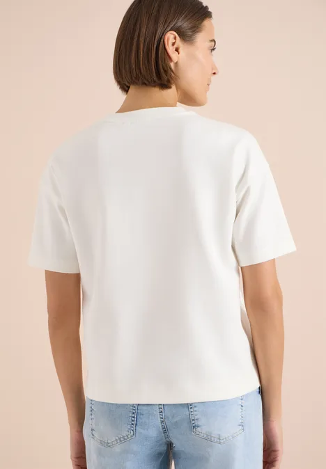 Bluza z krótkim rękawem z haftem vanilla white Osoba widziana od tyłu w prostym białym t-shircie i niebieskich jeansach.